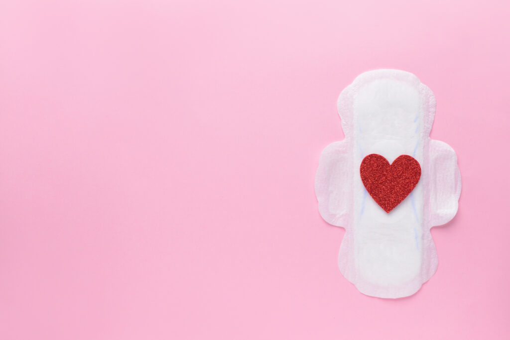 Menstrual pad with red heart on color background. Menstruation concept