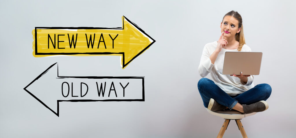 Old way or new way with young woman using her laptop on a grey background